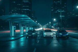 Carros elétricos à noite diante de uma estação de recarga rápida iluminada em ciano